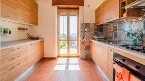 A modern kitchen with wooden cabinets, a tiled backsplash, and a view through the door. - La Terrazza Di Siracusa - Roomy And Bright Flat (Syracuse)