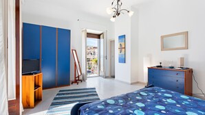 Een slaapkamer met een bed, een televisie, een dressoir en een deur die uitkomt op een balkon.
