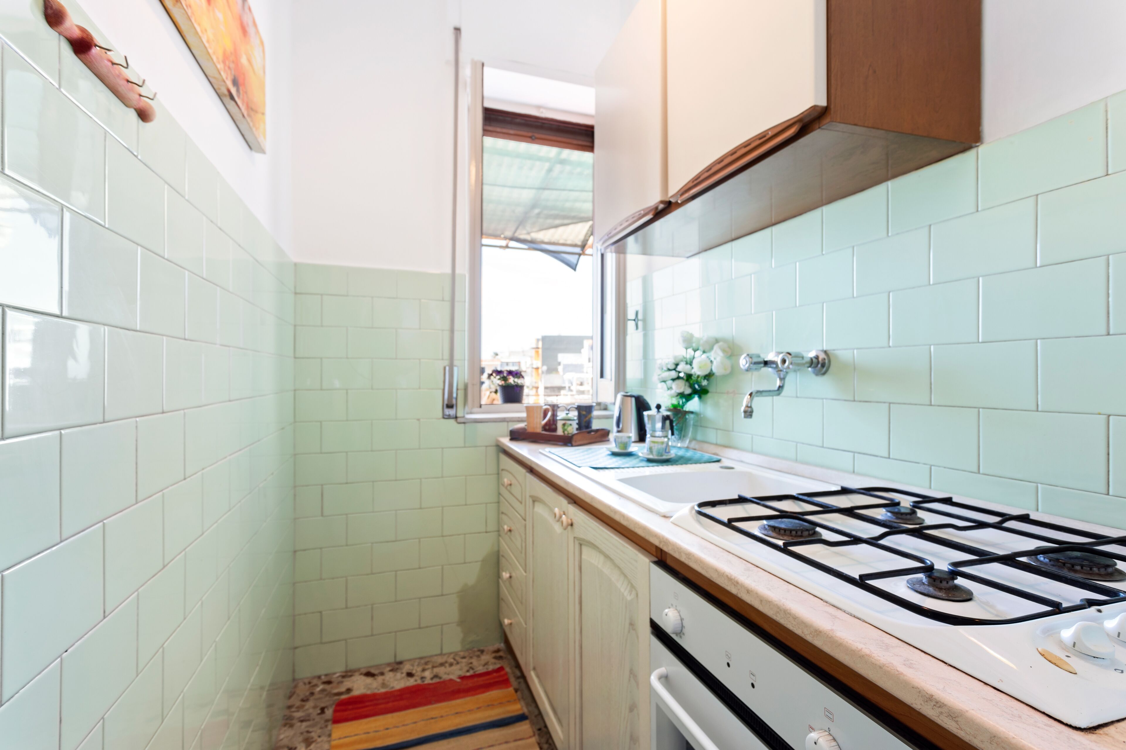 A kitchen with a gas stove, white cabinets, and a window.