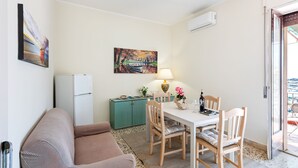 Een ruimtelijk ingerichte leefruimte met een eethoek, een kitchenette en een slaapbank.