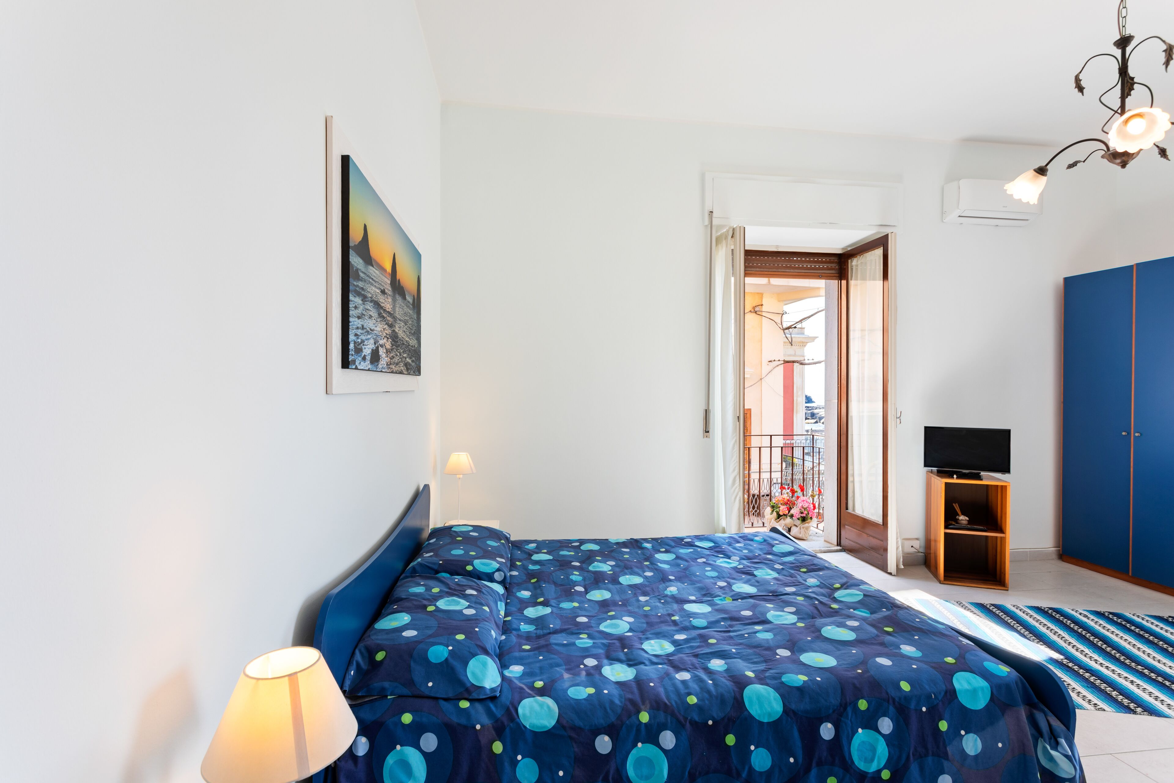 A bedroom with a bed, a lamp, a TV, and a wardrobe.