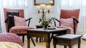 A cozy seating area with two upholstered chairs, a small wooden table with a vase of flowers, and a mirror on the wall. - Charming APT Old Town Prague (Prague)