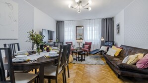 A modern living room with a wooden herringbone floor, a brown leather sofa, and a dining area with a wooden table and chairs. - Charming APT Old Town Prague (Prague)
