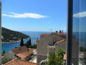 A stone building with a tiled roof, a view of the sea, and a clear sky.