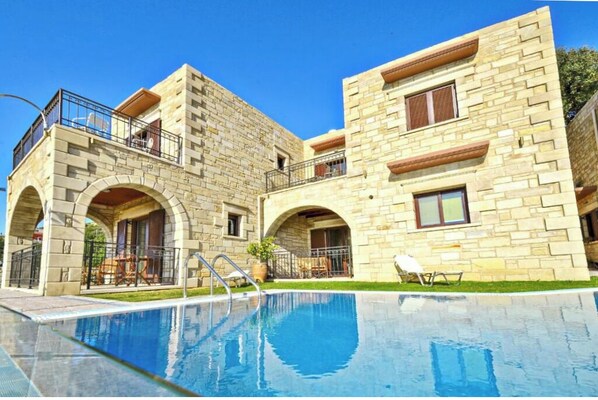 Un edificio de piedra de dos pisos con una piscina delantera.