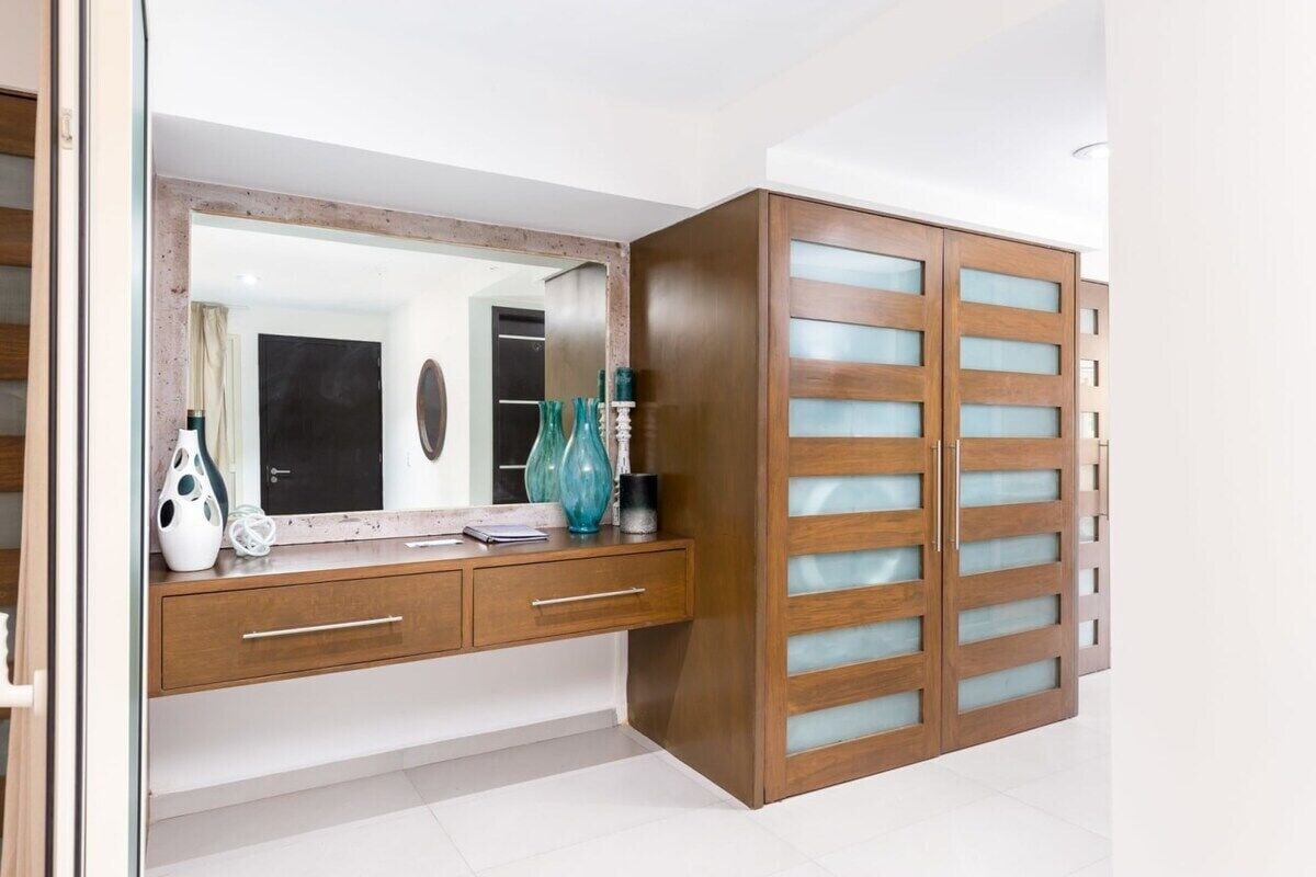 Ein modernes Badezimmer mit einem Holzkosmetikschrank, einem großen Spiegel und einem Schrank mit Glastür.