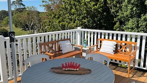 A deck with a round table, two wooden benches, and a cutlery set on the table. - 2 Bellenger - Pet friendly two Bedroom house, located close the the beach and main street! (Nambucca Heads)