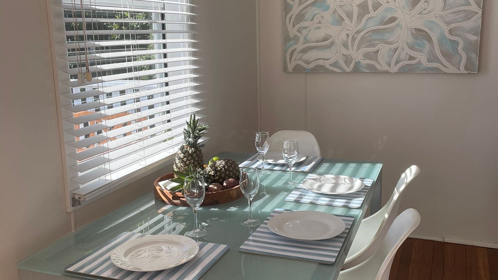 A dining table set with plates, glasses, and a centerpiece of pineapples.