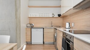 Eine kompakte Küche mit Geschirrspüler, Waschmaschine und Kaffeemaschine auf der Arbeitsplatte.