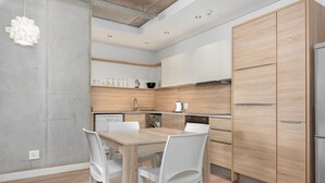 Eine moderne Küche mit einem Holzespeisebereich und Stühlen, integrierten Geräten und einer hellen Holzoptik an den Schränken.