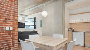Eine moderne Küche mit einem Holztisch und -stühlen, einer Ziegelwand und einem eingebauten Geschirrspüler.