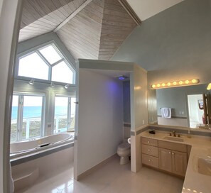 Een bad/douchecombinatie, een bubbelbad, een haardroger, handdoeken