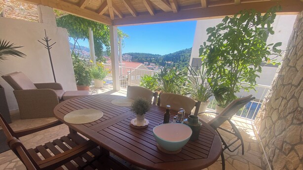 Uma mesa de madeira com cadeiras, uma tigela, uma garrafa e um vaso com planta.