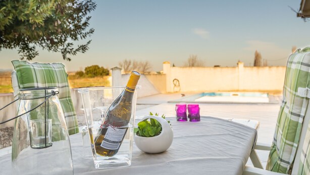 Une table avec une bouteille de champagne, un verre, une petite plante en pot et deux verres violets.