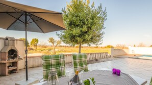 Une terrasse extérieure avec une table dressée pour deux personnes, un barbecue et une vue sur la campagne.