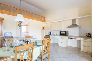 A kitchen with wooden cabinets, a microwave, and a dining area with a table set for four.