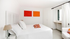 Une chambre à coucher avec un lit, une table de chevet avec une lampe, une chaise et une fenêtre avec des rideaux.