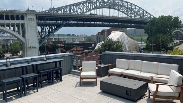 Terraço no telhado com área de estar externa, um sofá grande e vista para uma ponte.