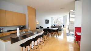 Cozinha moderna com uma ilha central, banquetas e uma área de jantar com uma cadeira vermelha.