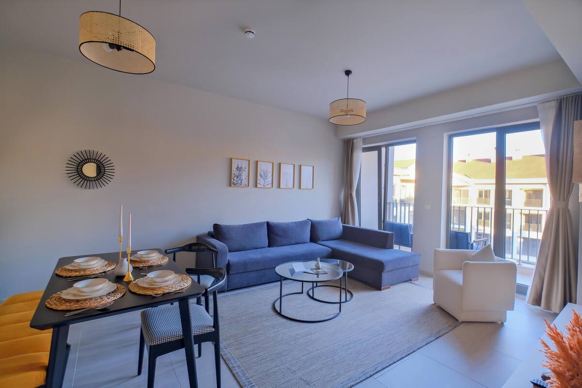 A modern living room with a sofa, a dining table set with plates, and a coffee table.