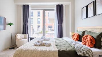 Habitación de hotel con cama, sillón, lámpara de pie y vista al exterior.