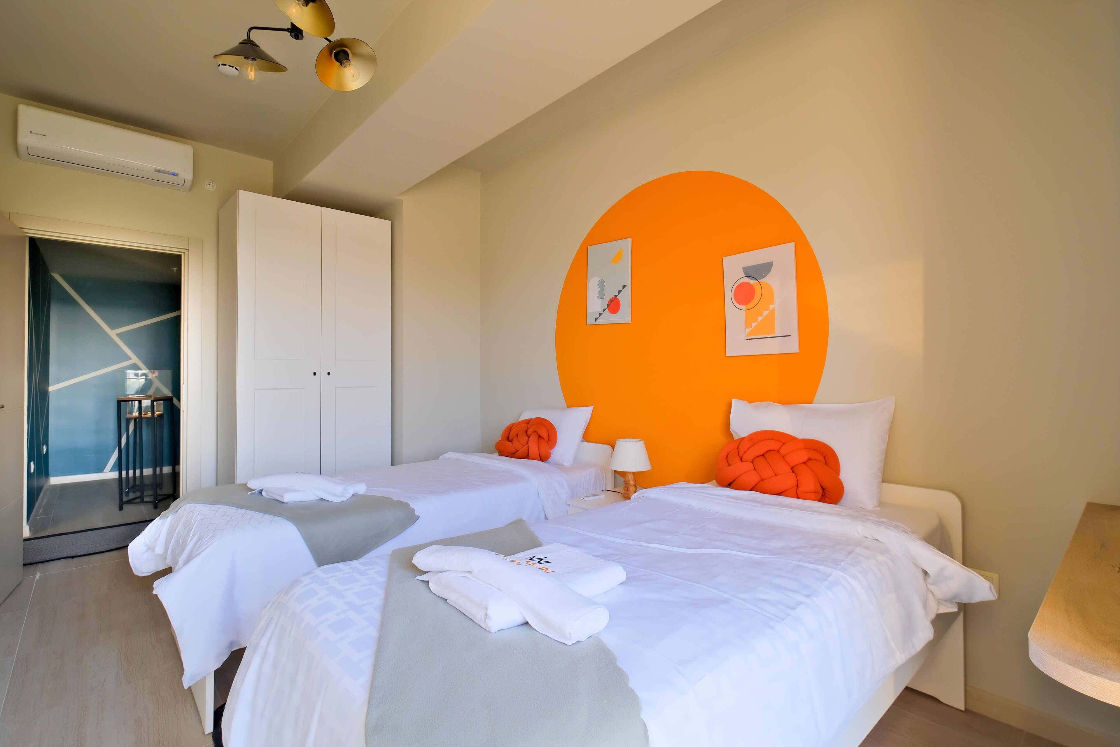 Een hotelkamer met twee bedden, een garderobe, een bureau en een stoel.