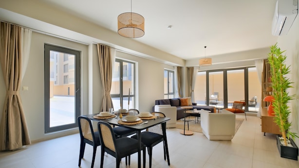 Een moderne woonkamer met een eethoek, grote ramen en uitzicht op buiten.