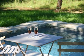 A poolside table with two glasses of red wine.
