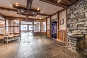 A spacious lobby with a stone wall, wooden beams, and a bench. - 200m from resort center, 4th floor, view valley, fitness, swimming pool, sauna, hammam, balcony, tv (Saint-Martin-de-Belleville)
