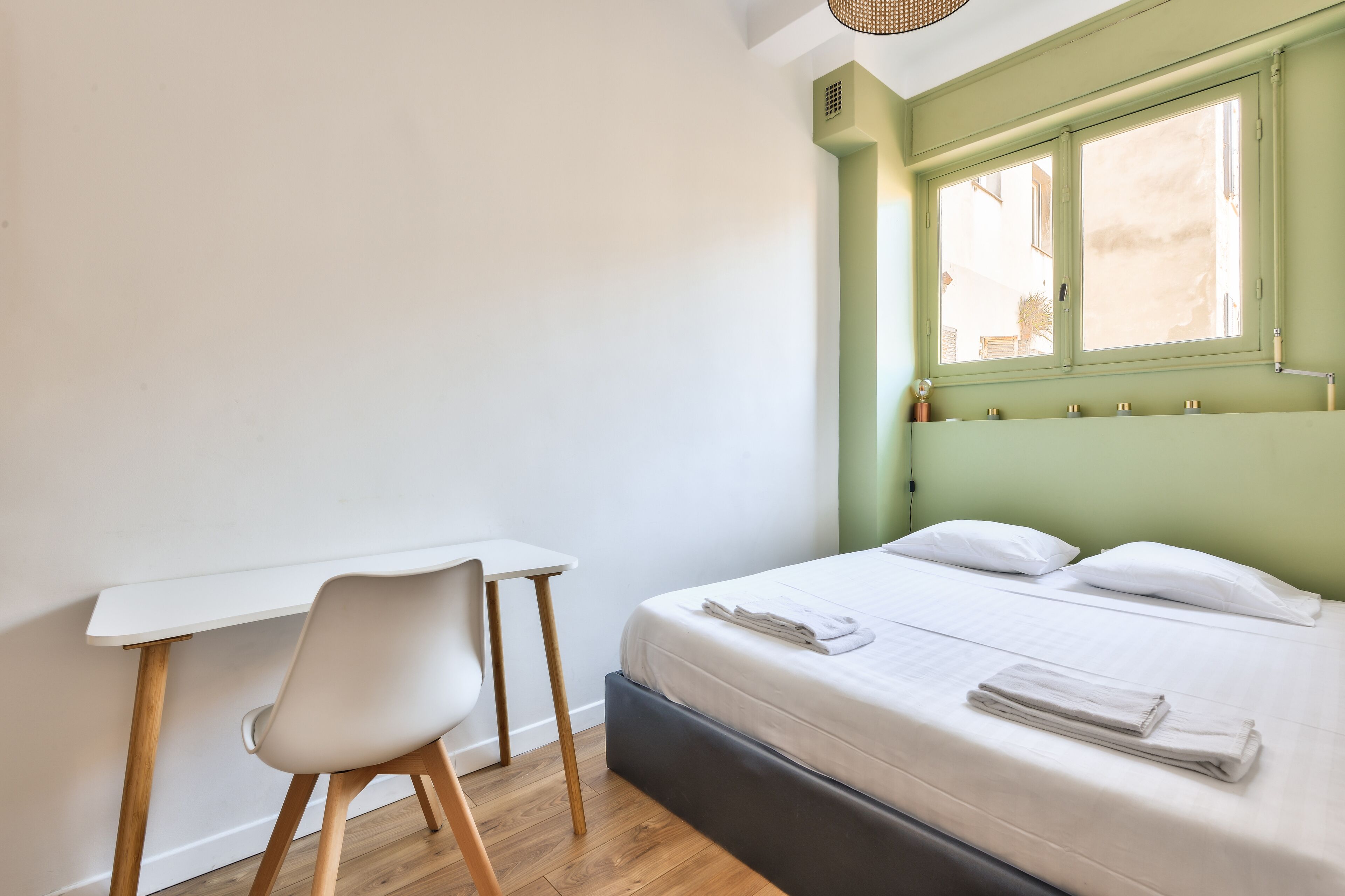 A bedroom with a bed, a desk, and a chair.