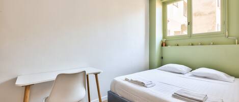 A bedroom with a bed, a desk, and a chair.