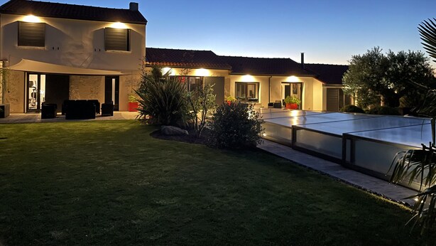 Une maison à deux étages dotée d’un patio couvert, d’un espace salon extérieur et d’une pelouse bien entretenue.