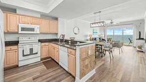 A modern kitchen with wooden cabinets, a built-in microwave, and a central island. - Top-Rated Comfort – Guest-Praised "Nicest unit" – Gulf Front – Two King Beds (Gulf Shores)