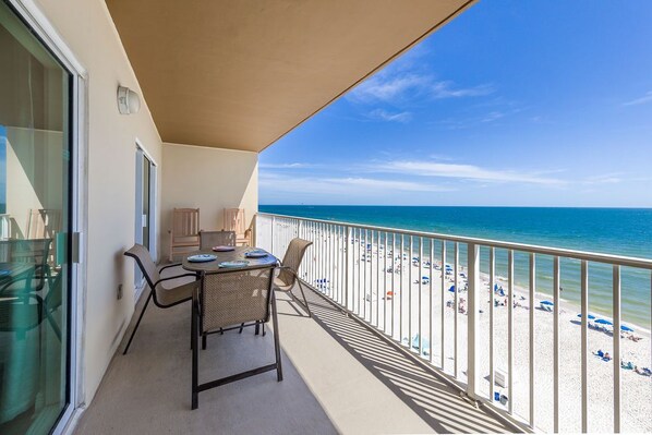 A balcony with a table and chairs overlooking a beach.