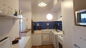 Una cocina compacta con electrodomésticos blancos, salpicadero de azulejos azules y piso estampado.