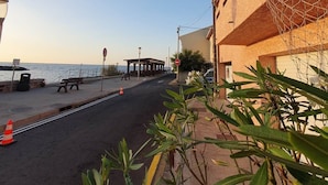Un paseo marítimo con bancos, una zona de estar cubierta y vistas al mar.