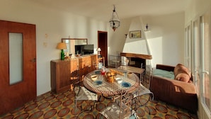 Una sala de estar con una mesa redonda, un sofá, una chimenea y un televisor.