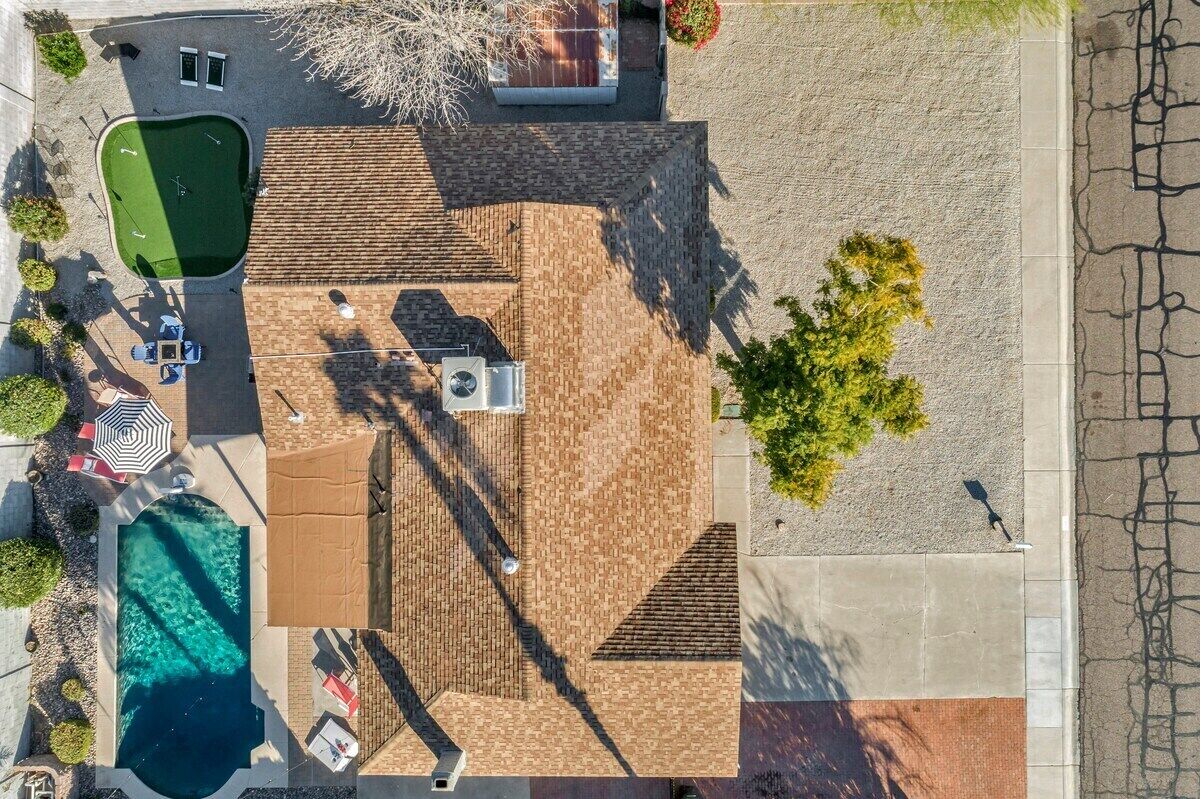 An aerial view of a property with a swimming pool, patio area, and a covered outdoor seating space.