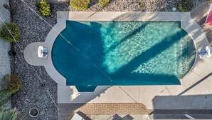 An aerial view of a swimming pool with a curved edge, surrounded by a pebble path, and equipped with lounge chairs and a small boat. - Nova Gypsy Vanner | Pool | Spacious Interior (Scottsdale)