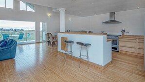 Een ruime woonkamer met een groot raam, een eettafel en een blauwe bank.