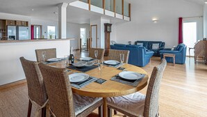 Een moderne, open woonruimte met een eethoek, keuken en zithoek.