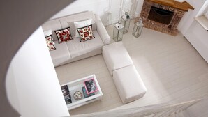 Een moderne woonkamer met een hoekbank, een salontafel met decoratieve objecten en een open haard.
