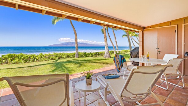 Une terrasse avec une table et des chaises, un barbecue et une vue sur l’océan.