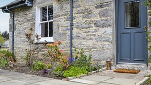A stone house with a dark blue door and a small window.
