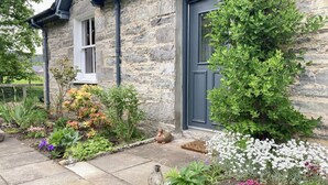 A stone house with a garden featuring various plants and flowers.