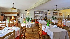 A restaurant with wooden tables and chairs, a fireplace, and wall-mounted clocks.