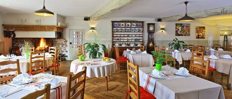 A restaurant with wooden tables and chairs, a fireplace, and wall-mounted clocks.