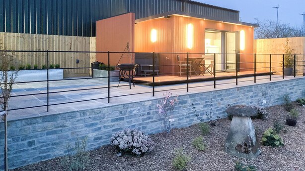 A modern building with a patio area, a barbecue grill, and a small seating area.