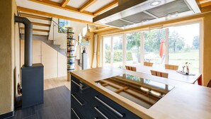 Een moderne keuken met een centraal kookeiland, ingebouwde apparatuur en grote ramen met uitzicht op de omgeving.