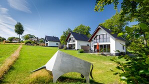 Een woonwijk met moderne huizen, een gazon en een grote betonnen sculptuur.
